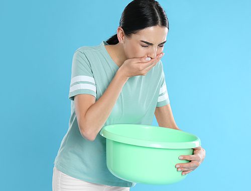 Woman with basin suffering from nausea on light blue background.